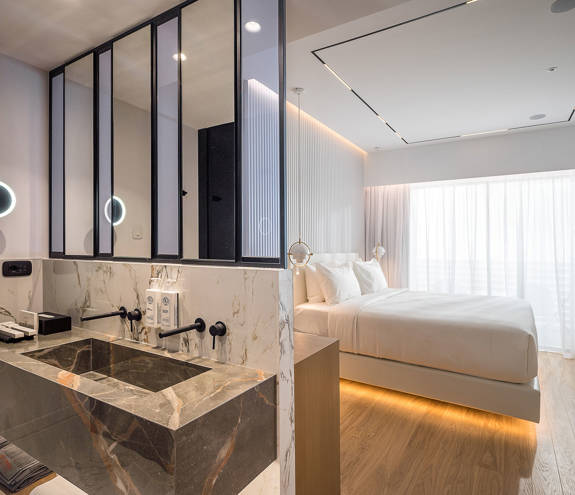 Ethereal White Resort Heraklion Deluxe Suite washbasins and the double bed in the background